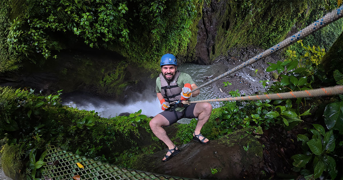 Traveler rappelling down a jungle waterfall during the Rainforest Falls adventure in La Fortuna, Costa Rica.