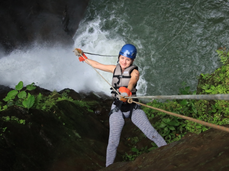 Woman rappelling down a waterfall during the Rainforest Falls canyoning adventure near La Fortuna, Costa Rica