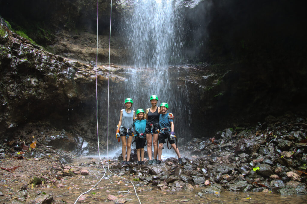 Family enjoying a guided canyoning experience beneath a waterfall with Pure Trek in La Fortuna, Costa Rica.