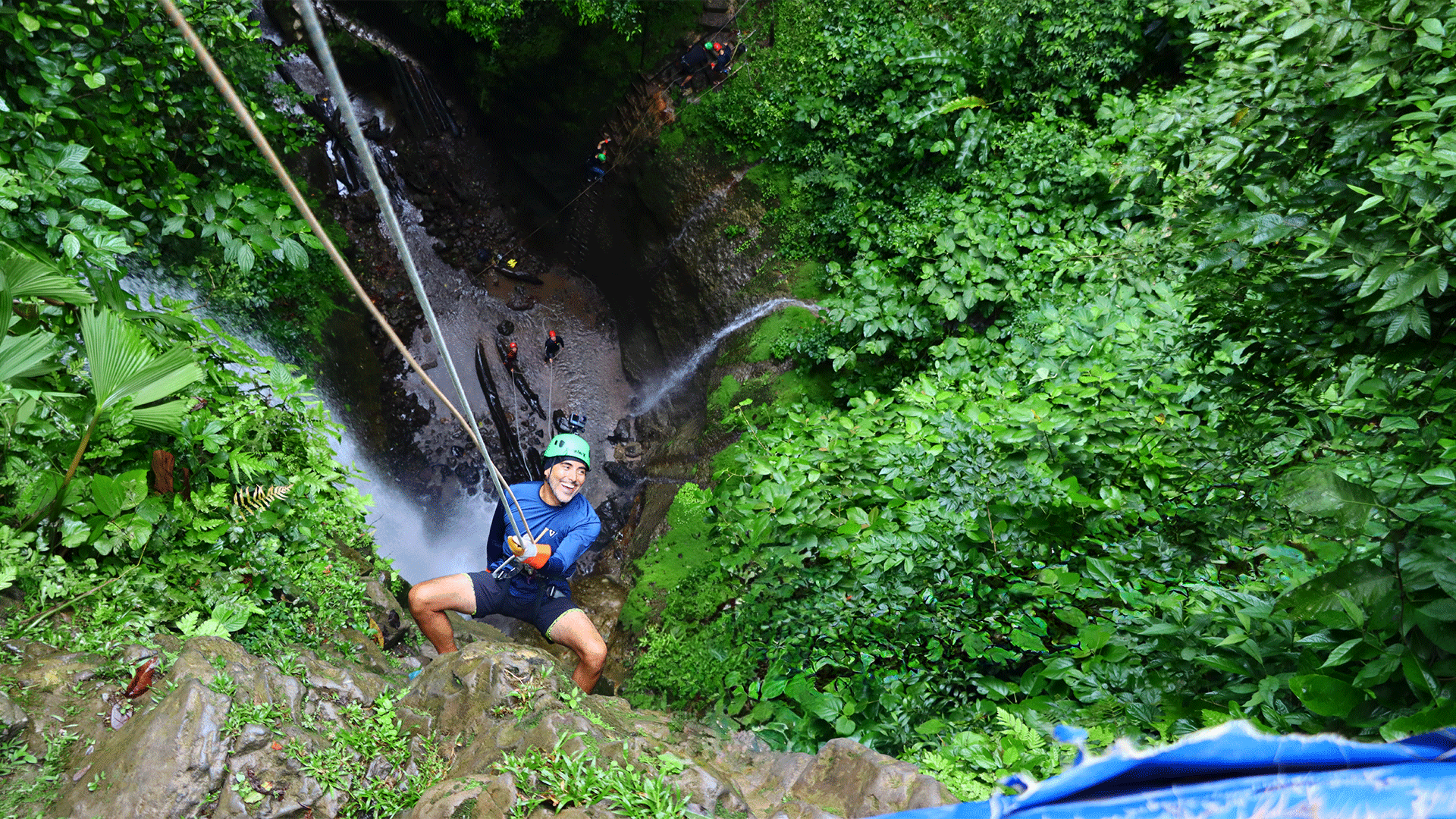 Guest rappelling down a jungle waterfall during the green season adventure in Arenal, Costa Rica.