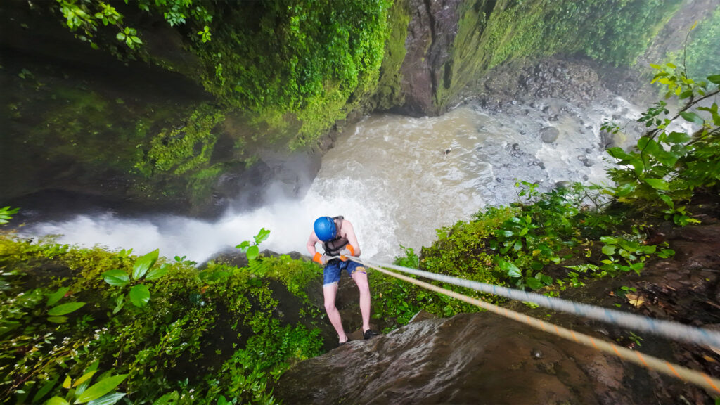 Guest rappelling down a high jungle waterfall during the Rainforest Falls adventure in Arenal, Costa Rica.