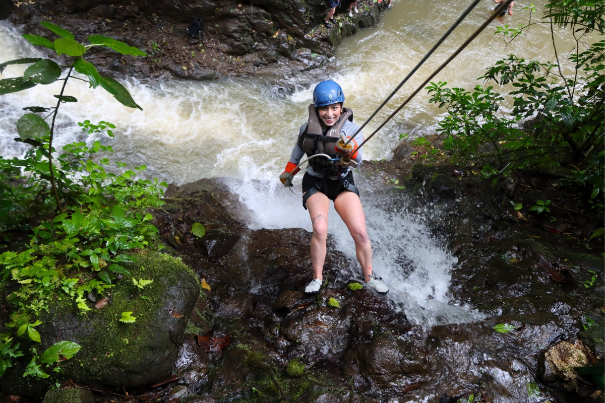 Guest rappelling through a rainforest waterfall during the Rainforest Falls canyon adventure in Arenal, Costa Rica.