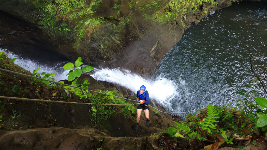 Guest rappelling beside a waterfall during the Rainforest Falls canyon adventure in Arenal, Costa Rica.