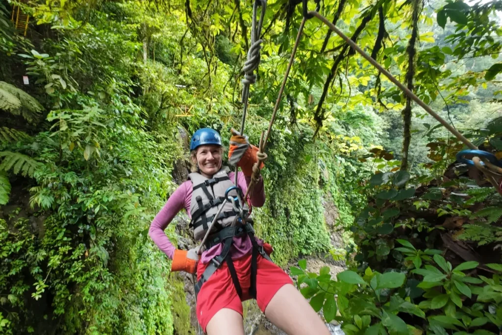 Smiling guest canyoning through the rainforest during a green season adventure in Arenal, Costa Rica.