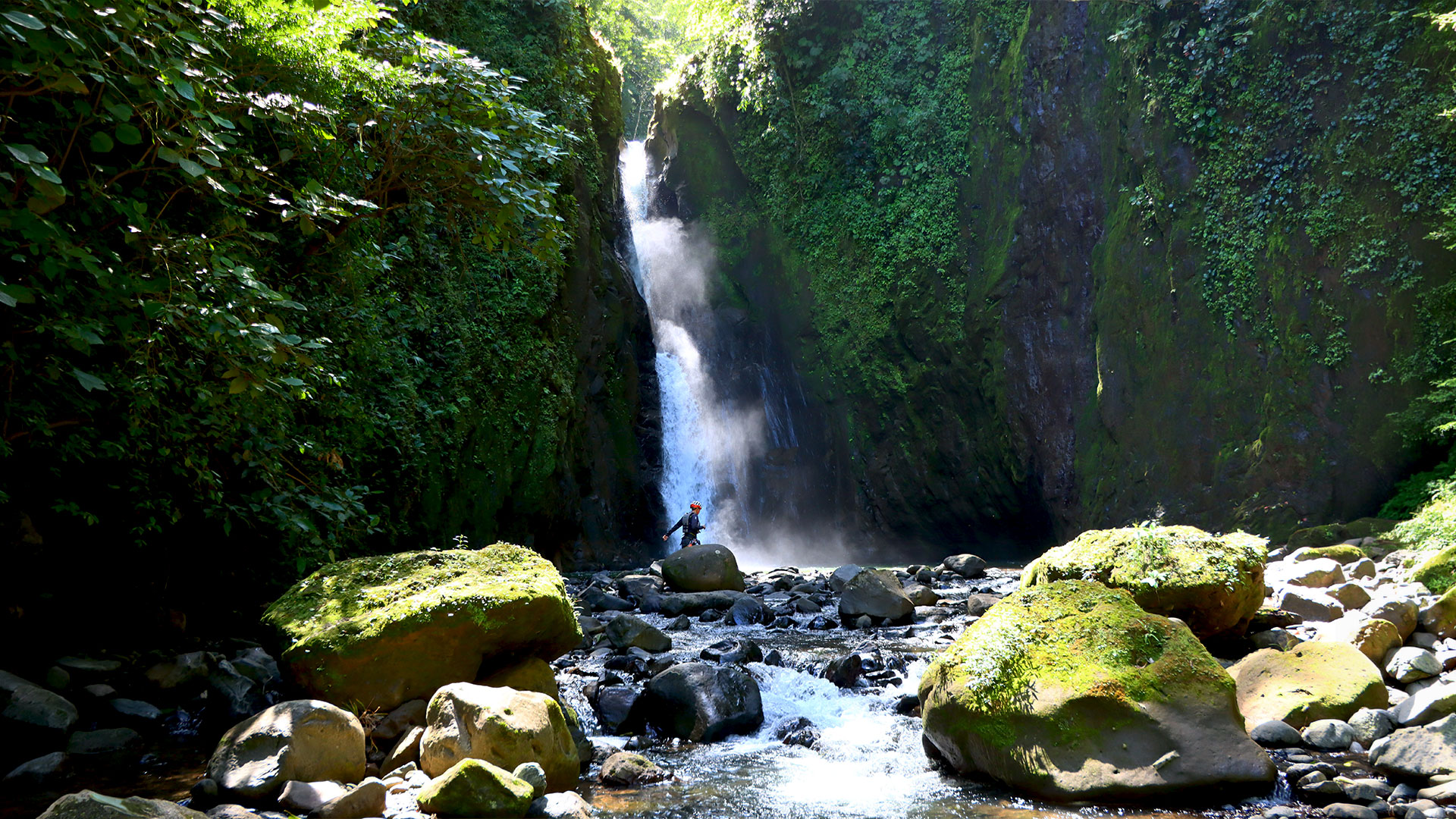 Guest exploring a large jungle waterfall in Arenal during a green season adventure in Costa Rica.