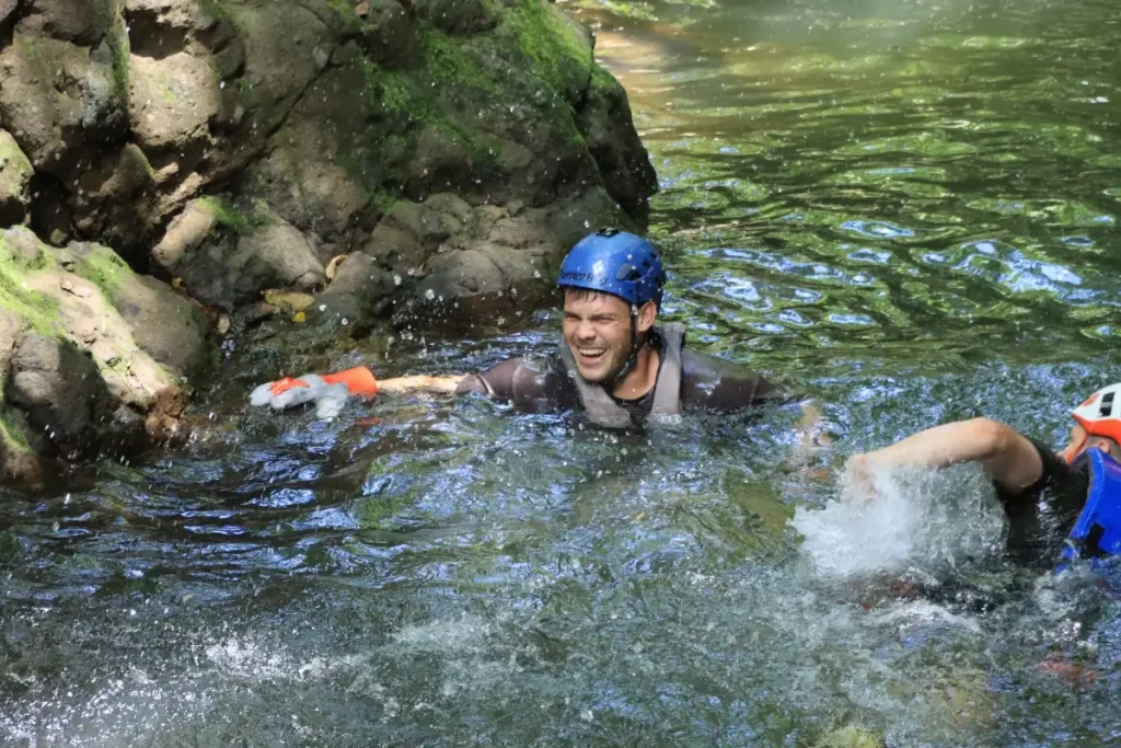 Guest enjoying a canyon pool after a waterfall jump during the Rainforest Falls adventure in Arenal, Costa Rica.