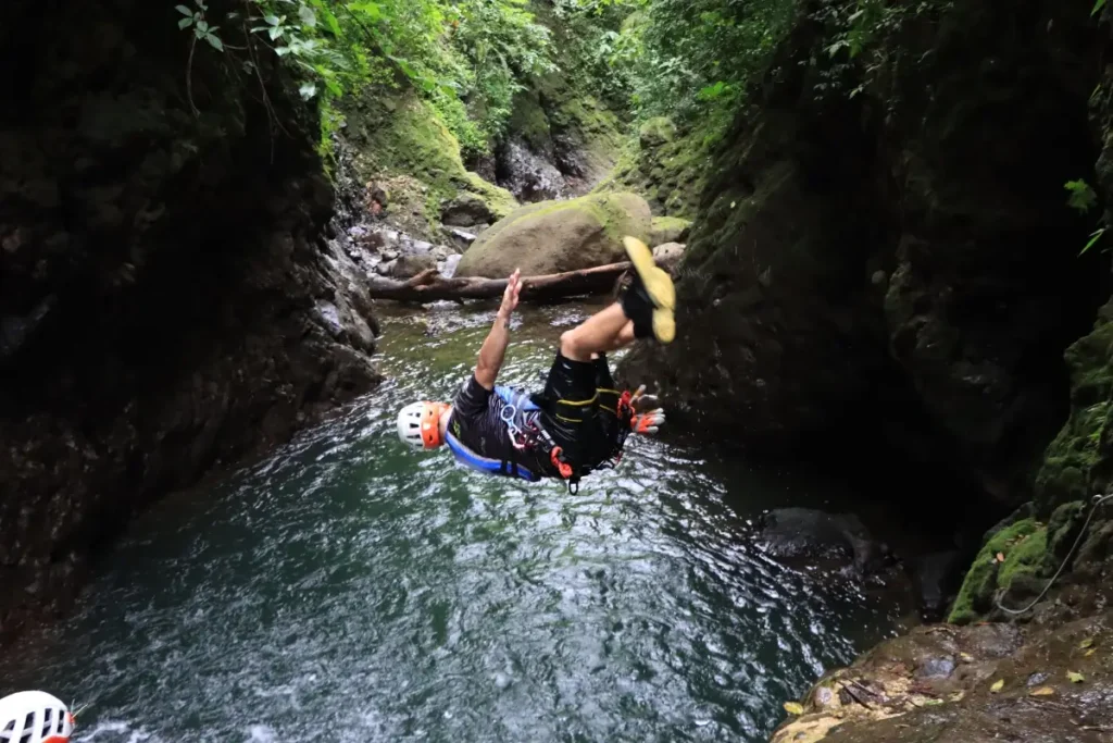 Guest jumping into a canyon pool during the Rainforest Falls adventure in Arenal, Costa Rica.